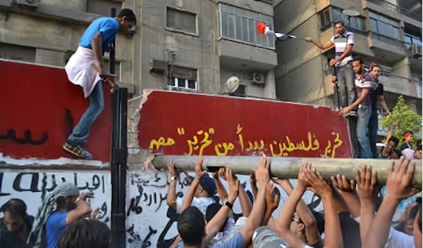 متظاهرون يحطّمون جزءاً من الجدار الذي يحيط بالسفارة الإسرائيلية في القاهرة عام 2011 (من الويب)