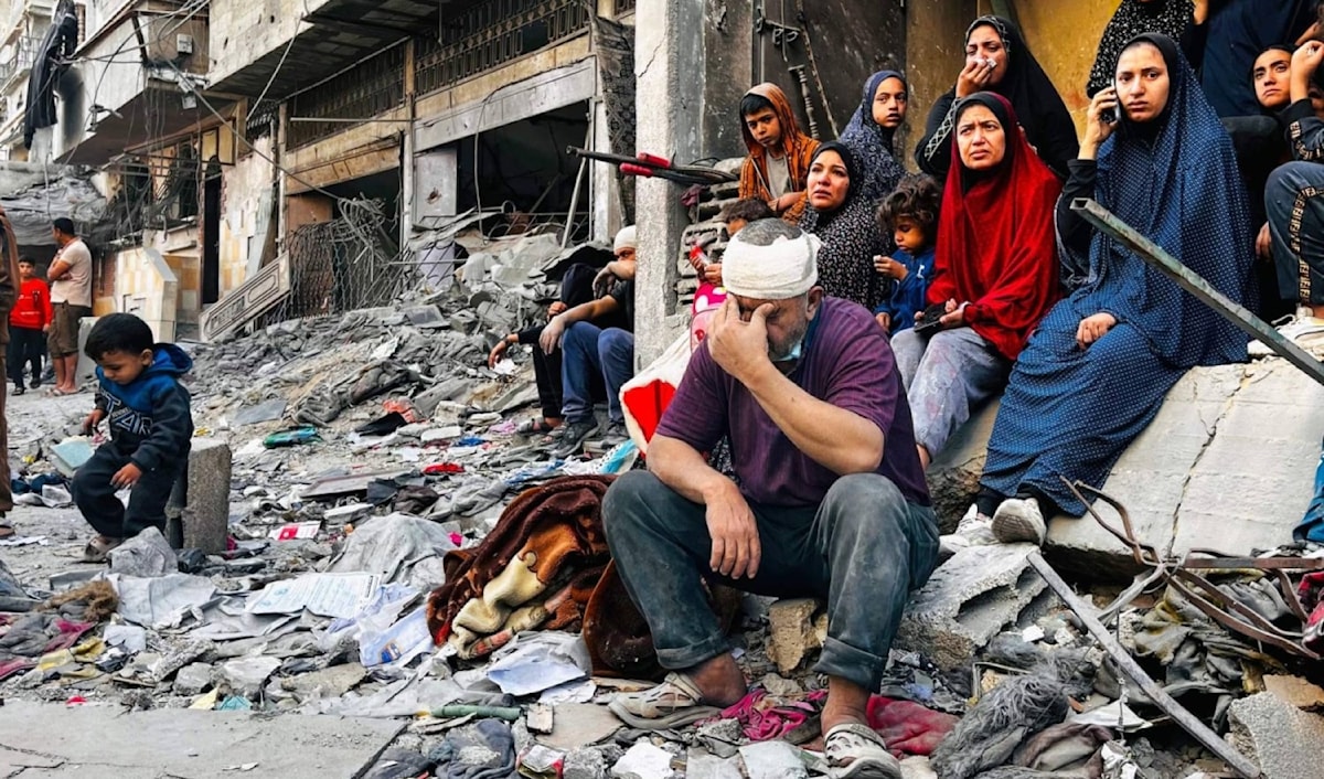 فلسطينيون يجلسون وسط ركام مبنى استهدفته غارة إسرائيلية في بيت لاهيا (أ.ف.ب)