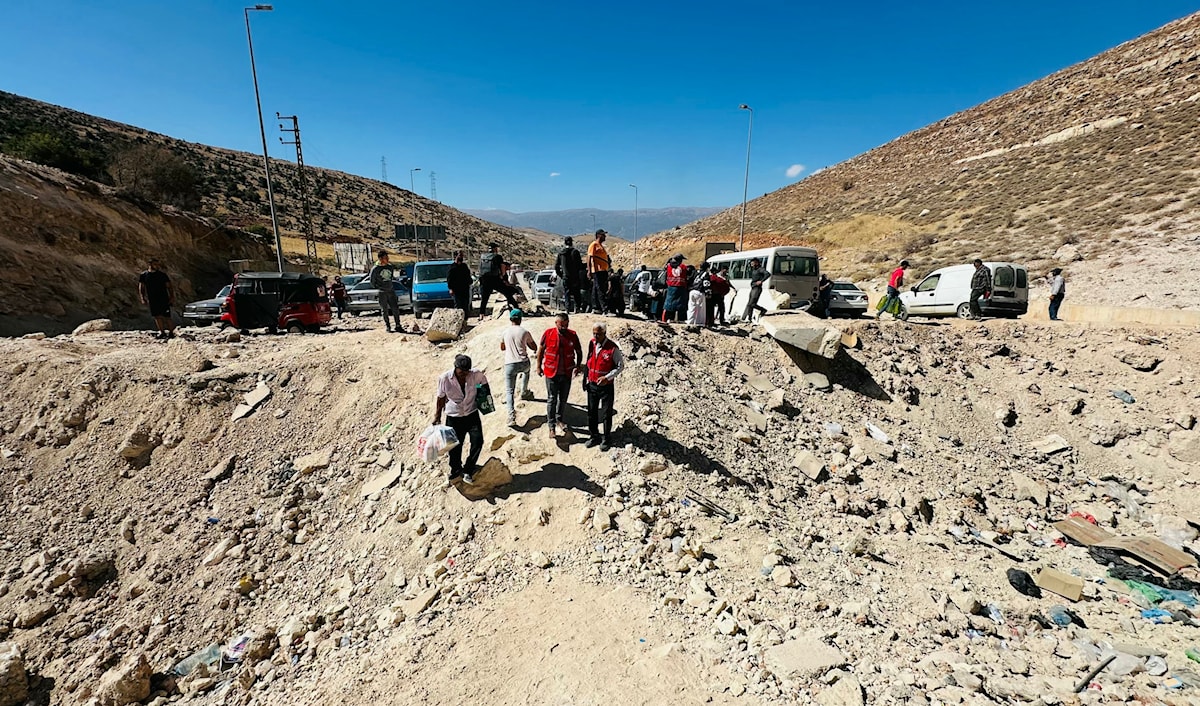 وافدون إلى سوريا يعبرون الطريق المؤدي إلى معبر المصنع - جديدة يابوس الذي كان تعرّض لعدوان إسرائيلي، مشياً على الأقدام (أ ف ب)