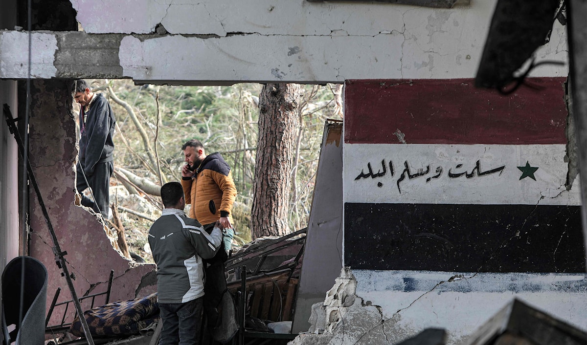 أشخاص يتفقدون الدمار في موقع مستودع أسلحة تعرض للقصف الإسرائيلي في ريف طرطوس (أ ف ب)