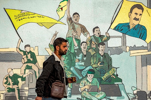 جدارية تمثل عناصر من "قسد" يرفعون أعلاماً وصوراً لعبدالله أوجلان في القامشلي (أ ف ب)