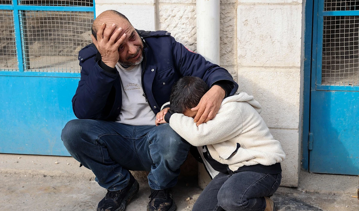 فلسطيني وابنه أمام مستشفى جنين الحكومي بعد استشهاد أحد أفراد عائلته (أ ف ب)