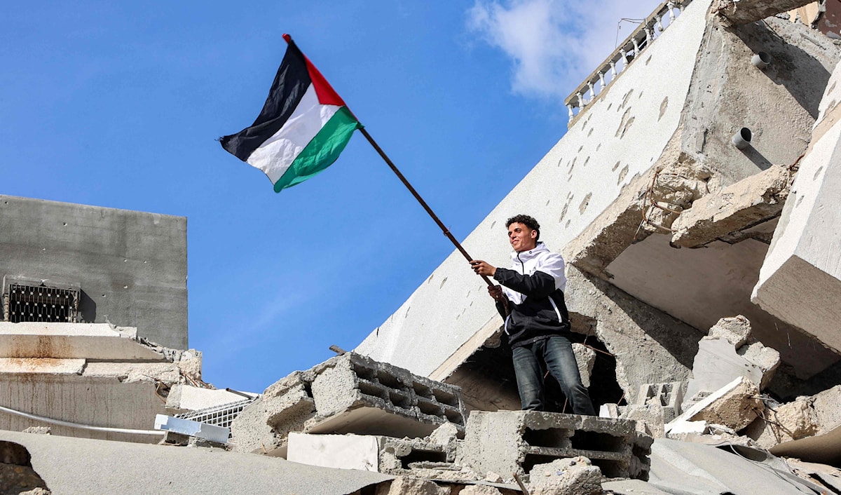 رفع العلم الفلسطيني على ركام أحد المنازل في مخيم جباليا (أ ف ب)