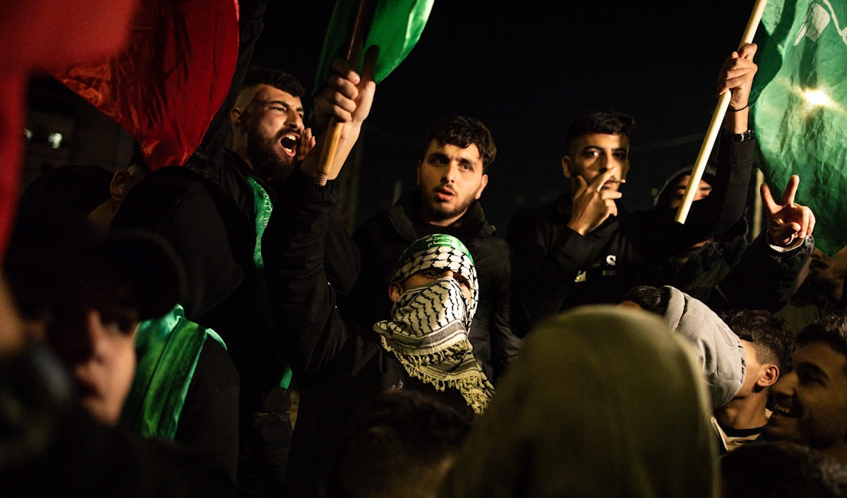 فلسطينيون بالكوفيات والأعلام الخضر ينتظرون في بيتونيا وصول أسرى مفرج عنهم من سجون الاحتلال (ا ف ب)