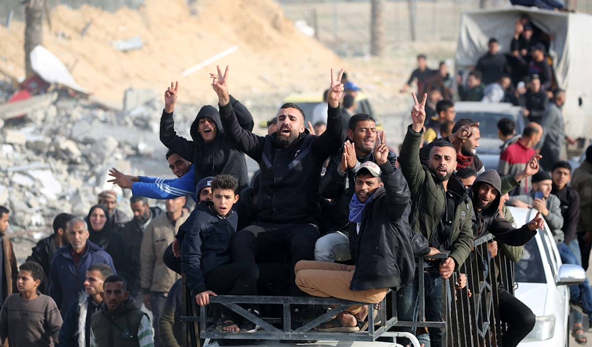 وقف الغزيون، ومن حولهم الدمار، رافعين شارات النصر (أ ف ب)
