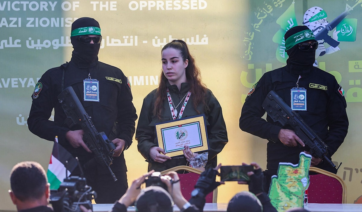المجندة تتوسط عناصر «القسام» على المنصة في جباليا (أ ف ب)