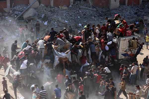 فلسطينيون يتسلّمون حصصاً غذائية بعد دخول شاحنات مساعدات من معبر كرم أبو سالم (أ ف ب)