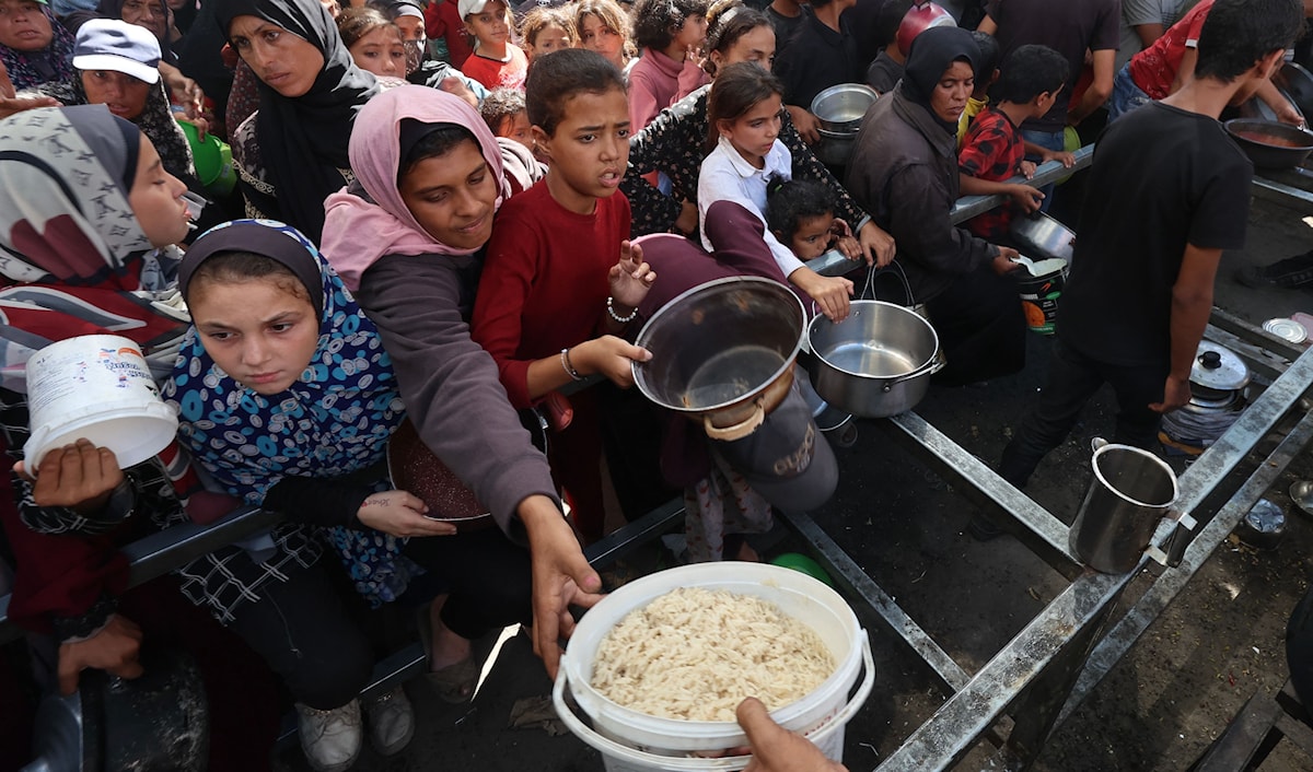 نازحون فلسطينيون يتلقّون حصصاً غذائية في مخيم النصيرات وسط قطاع غزة (أ ف ب)