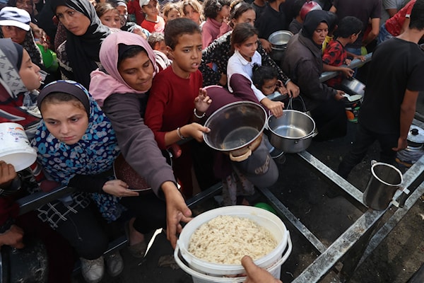 نازحون فلسطينيون يتلقّون حصصاً غذائية في مخيم النصيرات وسط قطاع غزة (أ ف ب)