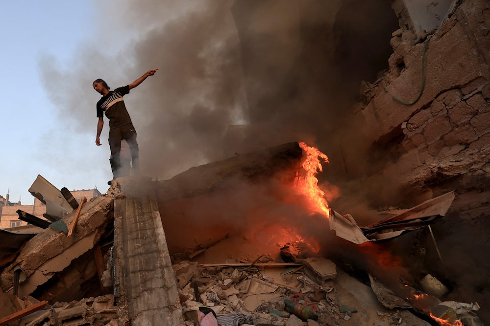 فلسطيني يقف على ركام مبنى منهار ومشتعل نتيجة ضربة إسرائيلية في 4 تشرين الثاني 2023 (أ ف ب)