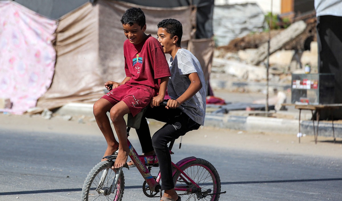 طفلان فلسطينيان يلعبان على دراجة هوائية في مخيم النصيرات وسط غزة (أ ف ب)