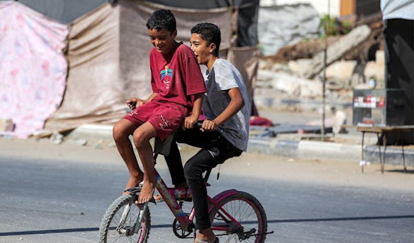 طفلان فلسطينيان يلعبان على دراجة هوائية في مخيم النصيرات وسط غزة (أ ف ب)