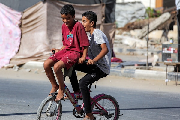 طفلان فلسطينيان يلعبان على دراجة هوائية في مخيم النصيرات وسط غزة (أ ف ب)
