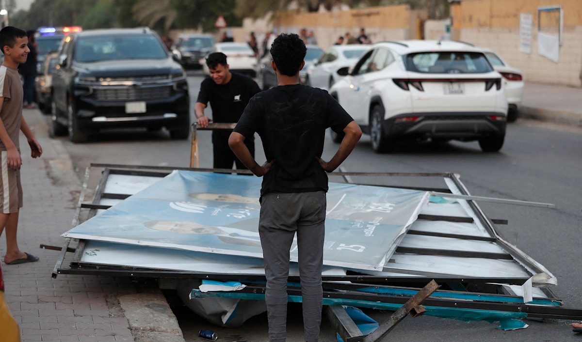عمال يزيلون إعلانات انتخابية من الشوارع بعد انتهاء الانتخابات في بغداد (أ ف ب)