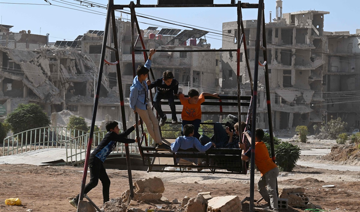 أطفال سوريون يلعبون في حديثة قرب مبان مدمّرة في داريا في ريف دمشق  (أ ف ب)