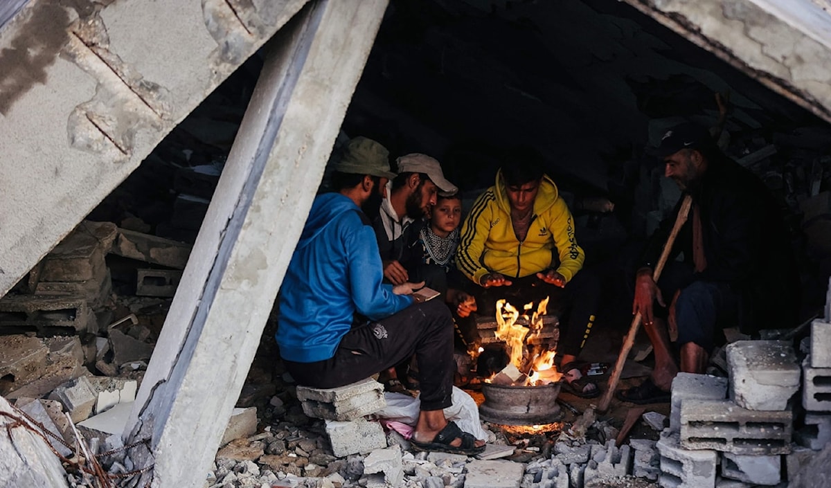نازحون يتحلّقون حول موقد نار للتدفئة في مدينة غزة (أ ف ب)