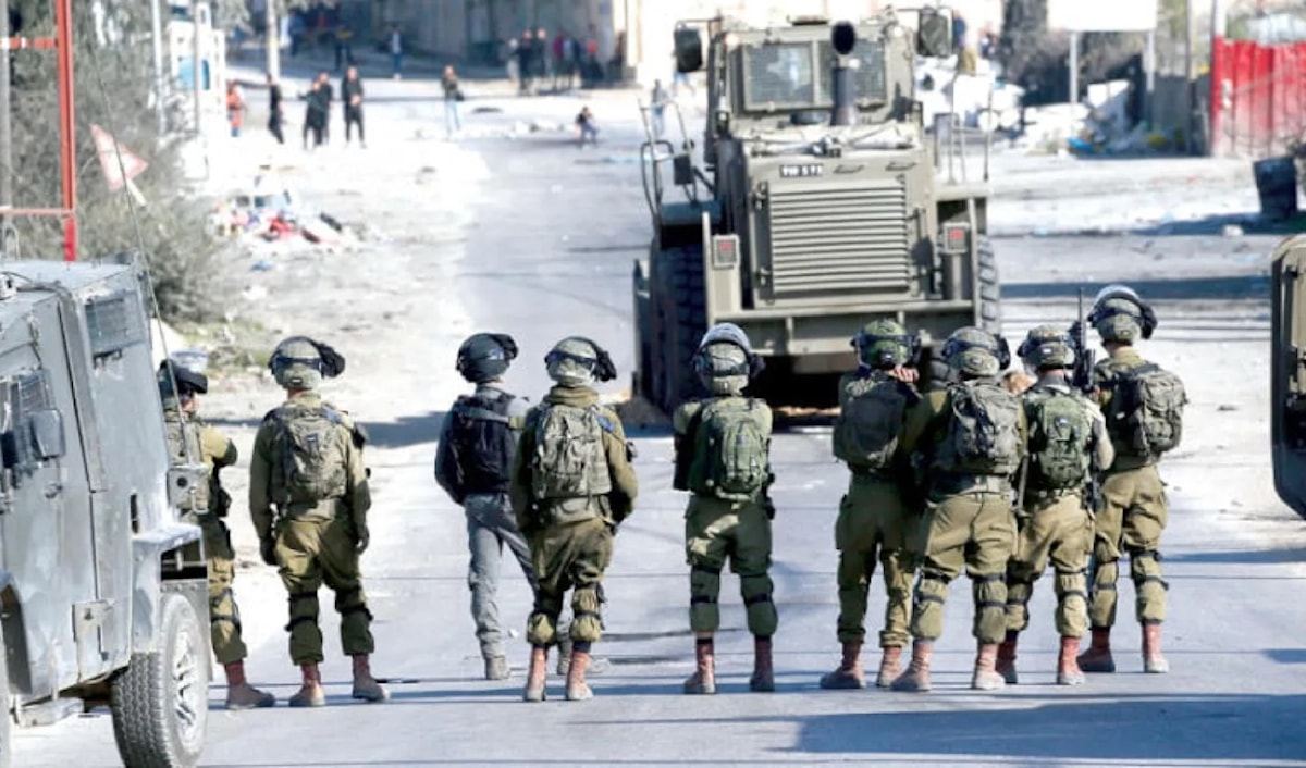 جنود إسرائيليون يراقبون شباناً فلسطينيين يرشقونهم بالحجارة في الضفة (أرشيف-فرانس برس)