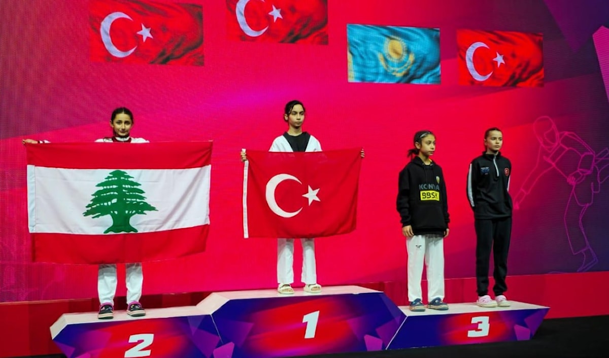 عبود (إلى اليسار) خلال تتويجها حاملةً العلم اللبناني