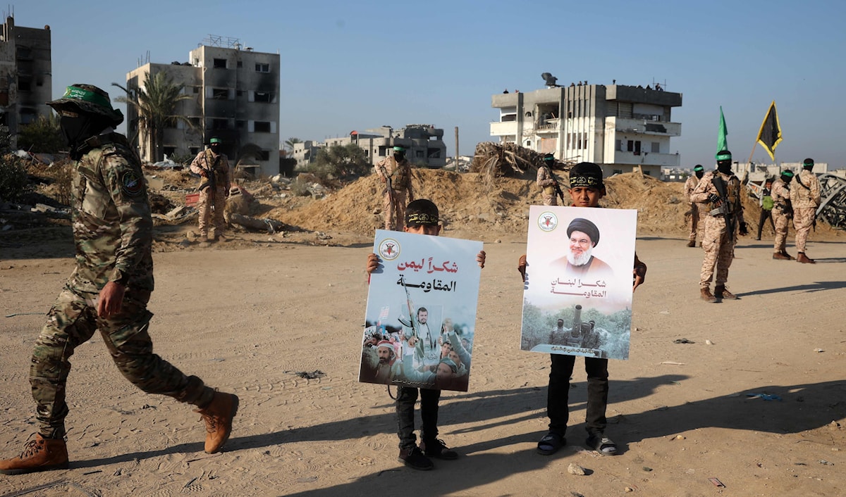 طفلان فلسطينيان في قطاع غزة يحملان ملصقين يشكران المقاومة على الإسناد (ا ف ب)