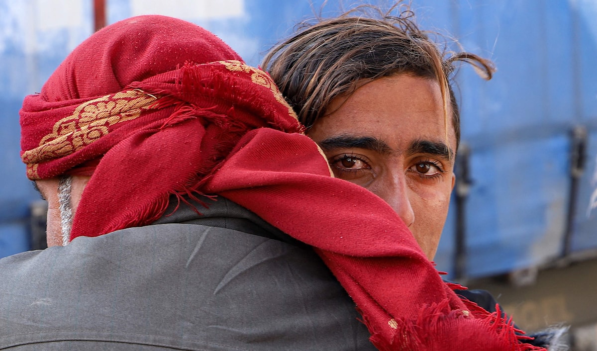 شاب عراقي يعانق قريباً في مخيم الهول الذي يضم عوائل عناصر تنظيم "داعش" في الحسكة، قبل عودته إلى العراق. (أ ف ب)
