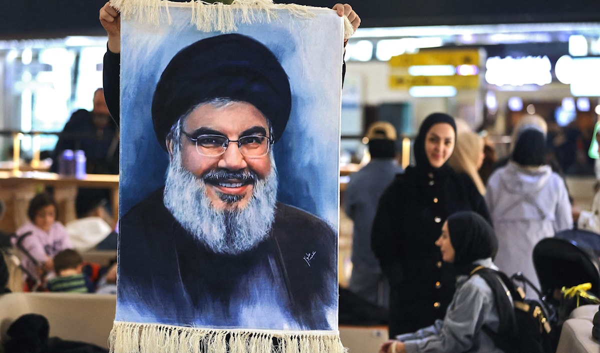 رفع صور للشهيد السيد نصر الله في مطار بغداد أثناء انتظار المسافرين موعد رحلتهم إلى بيروت أمس (أ ف ب)