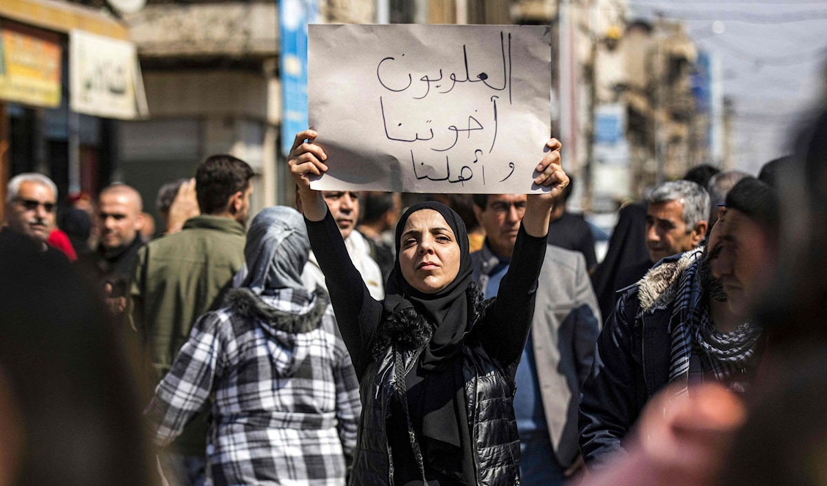 كردية سورية ترفع لافتة كتب عليها "العلويون أخوتنا وأهلنا" خلال تظاهرة في القامشلي (أ ف ب)