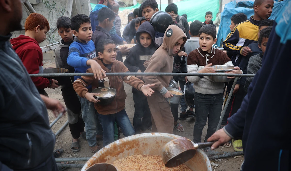 أطفال فلسطينيون ينتظرون وجبات من مطبخ خيري في مخيم النصيرات وسط قطاع غزة (أ ف ب)
