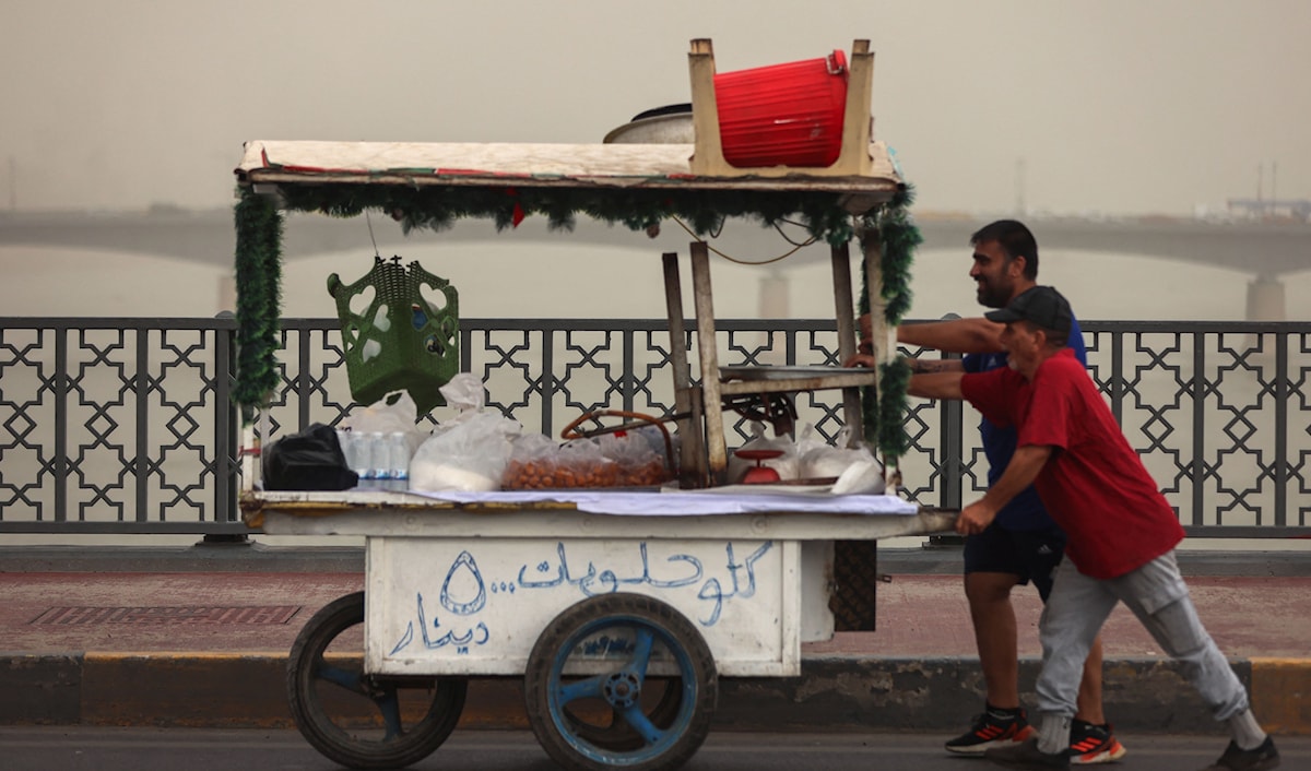 بائعان يعبران جسر السنك في بغداد وسط عاصفة رملية (أ ف ب)