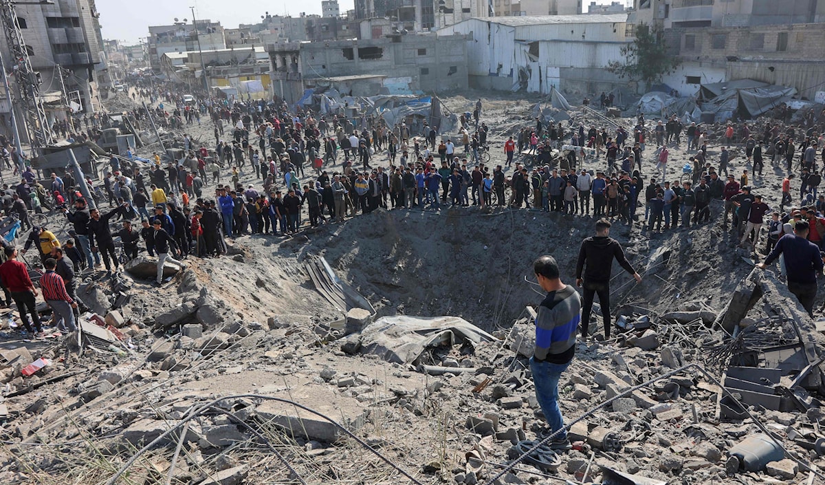 فلسطينيون يتحلّقون حول حفرة كبيرة أحدثها القصف الإسرائيلي في حي الزيتون في قطاع غزة (أ ف ب)