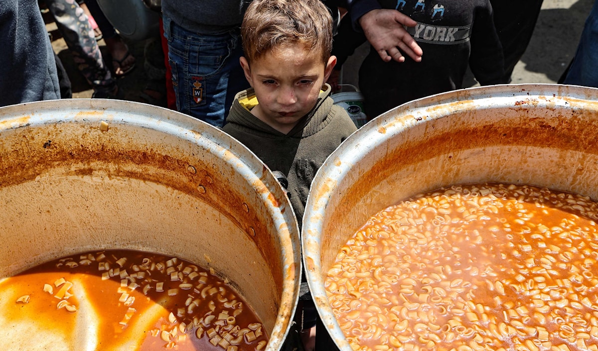 طفل فلسطيني ينتظر دوره للحصول على حصته من الطعام في مخيم النصيرات بغزة (فرانس برس)