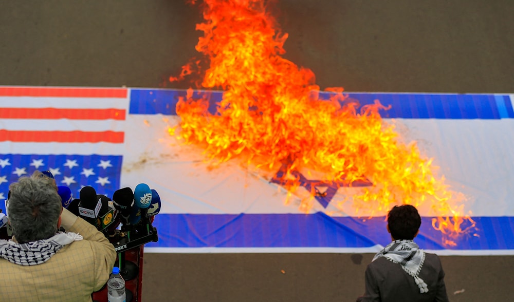 حرق العلمين الأميركي والإسرائيلي خلال تظاهرة في صنعاء (أ ف ب)