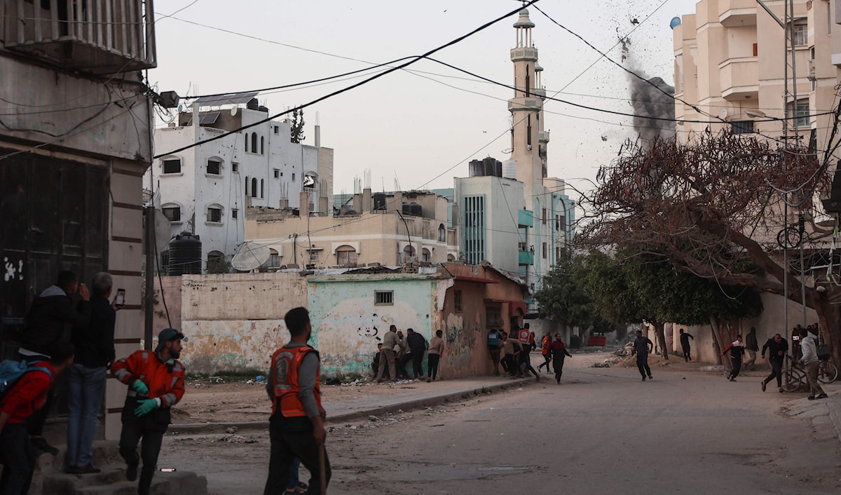 مسعفون ومواطنون فلسطينيون يحتمون أثناء قصف على حي التفاح في غزة (أ ف ب)