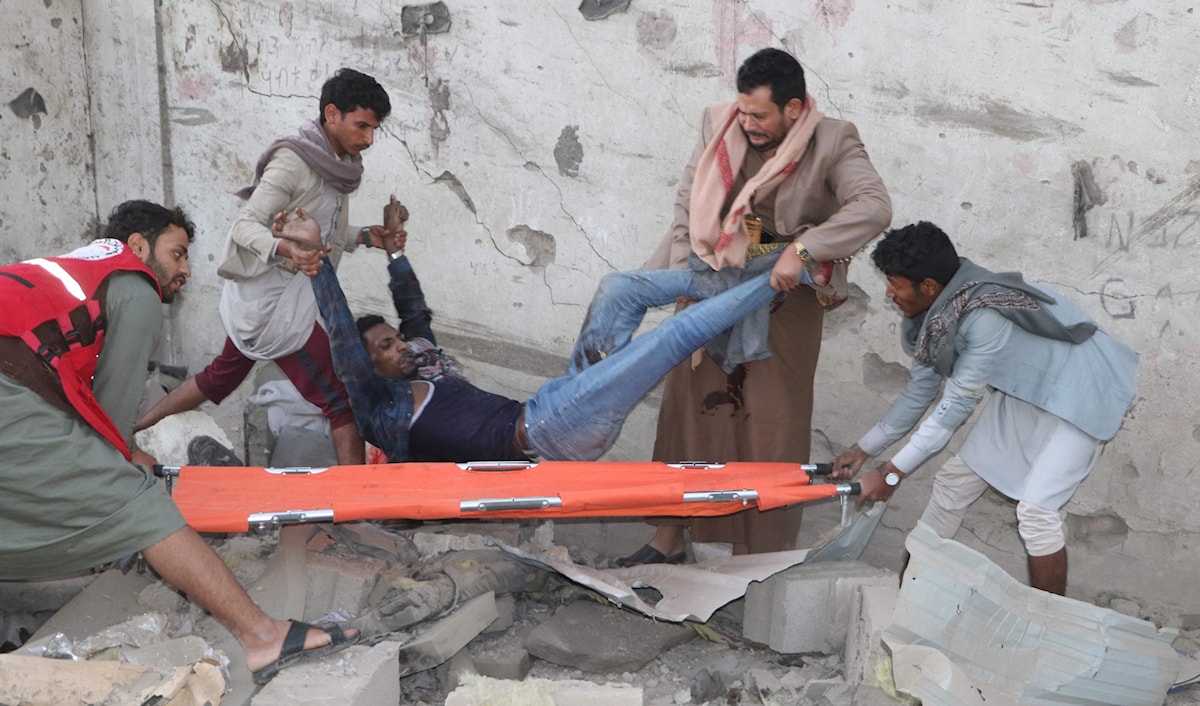 يمنيون ينقذون جريحاً أصيب في غارة على صعدة (أ ف ب)