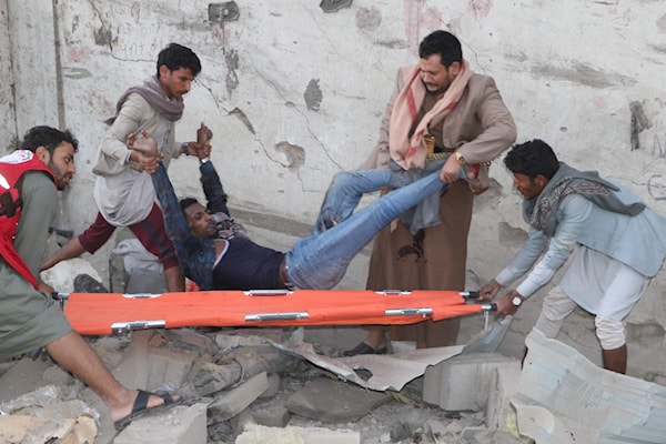 يمنيون ينقذون جريحاً أصيب في غارة على صعدة (أ ف ب)