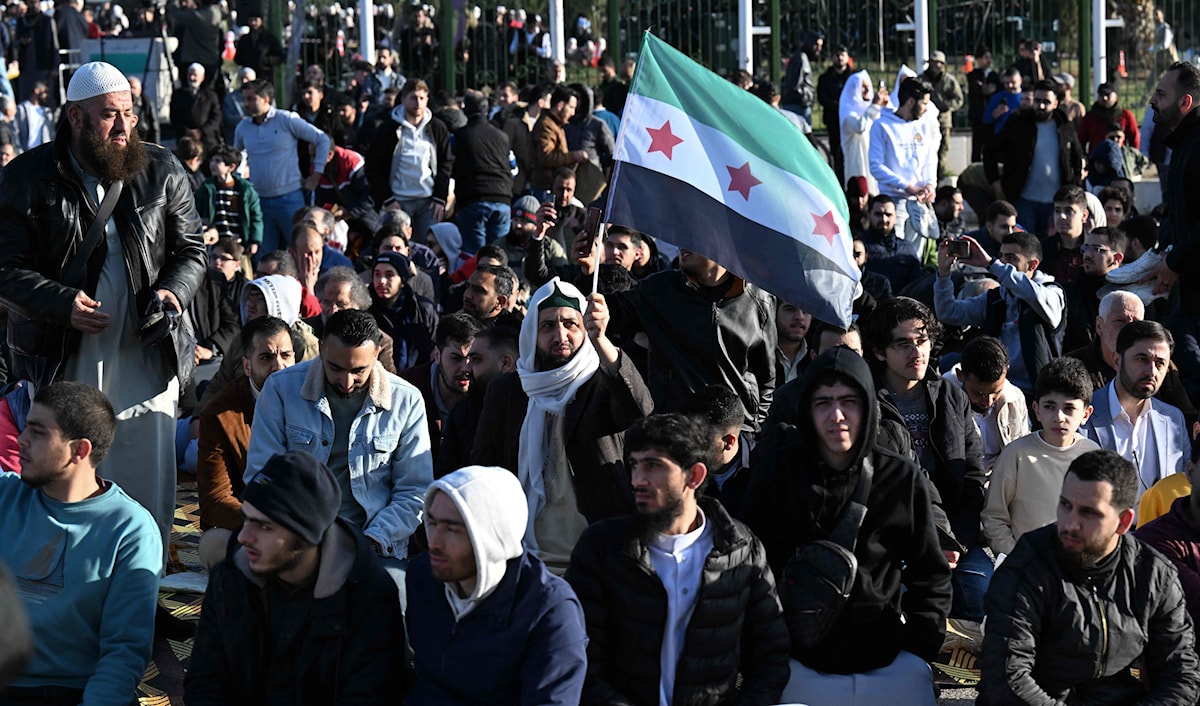 رفع الأهالي في الوقفة الاحتجاجية الأعلام الوطنية إلى جانب لافتات استنكارية (أ ف ب)