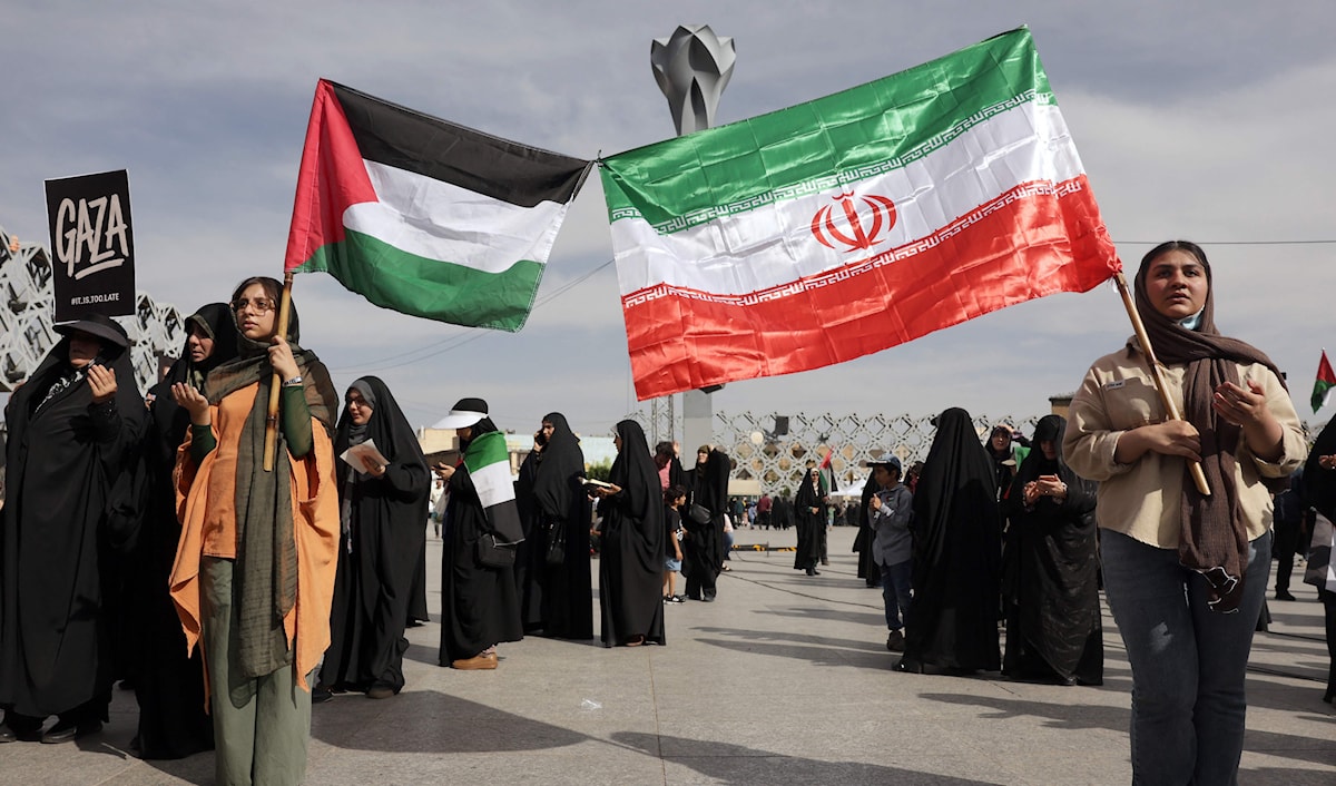 إيرانيات يرفعن العلمين الإيراني والفلسطيني خلال مسيرة في طهران (أ ف ب)