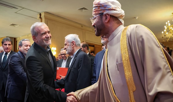 الرئيس الإيراني، مسعود بزشكيان، مصافحاً وزير الخارجية العماني، بدر البوسعيدي، في طهران (أ ف ب)