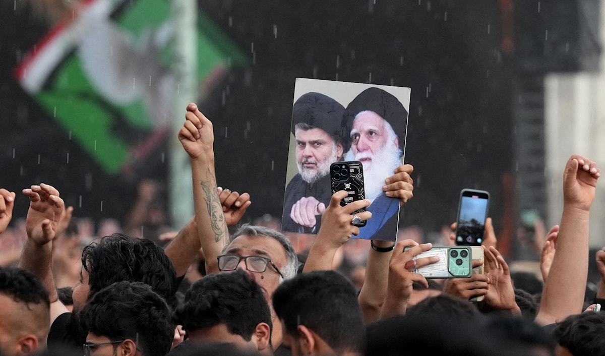 أنصار مقتدى الصدر يرفعون صوره مع والده السيد محمد صادق الصدر خلال إحياء ذكرى اغتيال الأخير في النجف (أ ف ب)