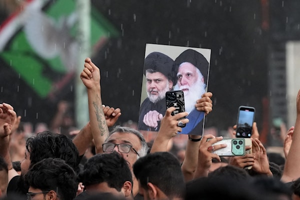 أنصار مقتدى الصدر يرفعون صوره مع والده السيد محمد صادق الصدر خلال إحياء ذكرى اغتيال الأخير في النجف (أ ف ب)