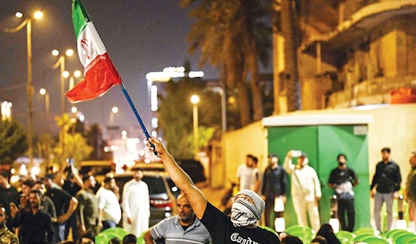 عراقي يرفع علماً إيرانياً لدى مشاركته في تظاهرة في البصرة (أ ف ب)