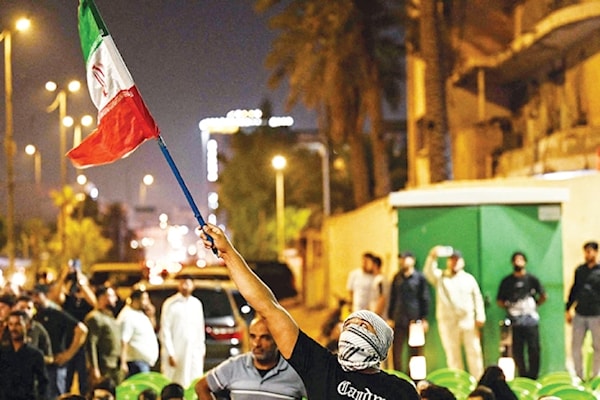عراقي يرفع علماً إيرانياً لدى مشاركته في تظاهرة في البصرة (أ ف ب)