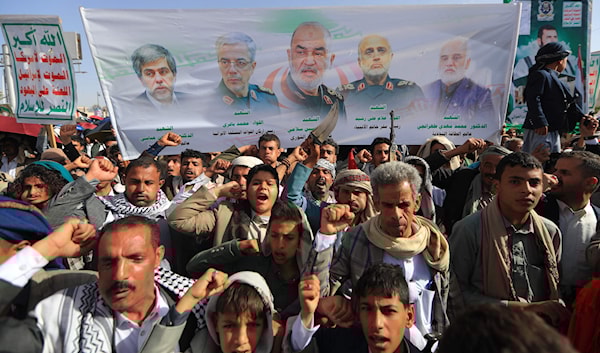 صور القادة العسكريين الإيرانيين الذين قتلوا في اليوم الأول للعدوان الإسرائيلي، على لافتة يرفعها يمنيون في صنعاء (أ ف ب)