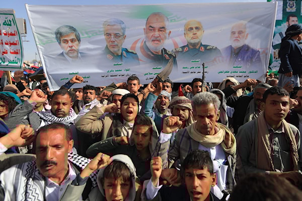 صور القادة العسكريين الإيرانيين الذين قتلوا في اليوم الأول للعدوان الإسرائيلي، على لافتة يرفعها يمنيون في صنعاء (أ ف ب)