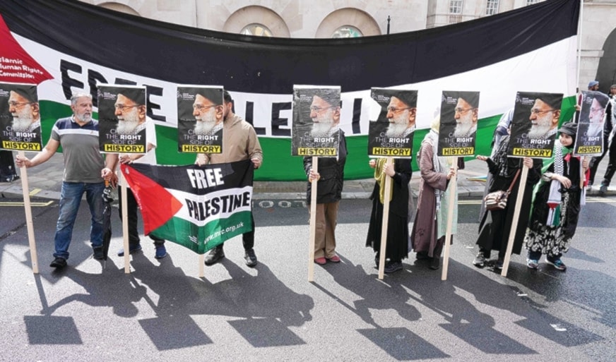 ناشطو حقوق إنسان يرفعون صور الخامنئي خلال مسيرة من أجل فلسطين أمام مقر رئاسة الحكومة البريطانية في لندن (أ ف ب)
