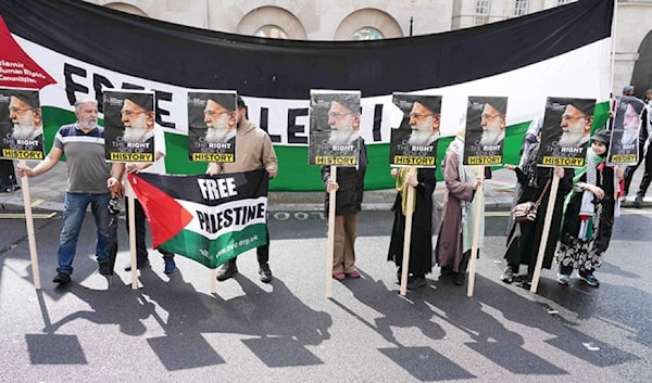 ناشطو حقوق إنسان يرفعون صور الخامنئي خلال مسيرة من أجل فلسطين أمام مقر رئاسة الحكومة البريطانية في لندن (أ ف ب)