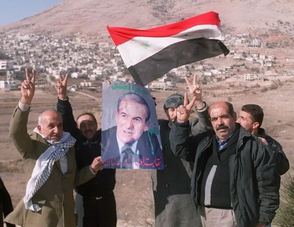 سوريون من مرتفعات الجولان يلوحون بالعلم السوري وصورة للرئيس الأسبق حافظ الأسد عام 1999