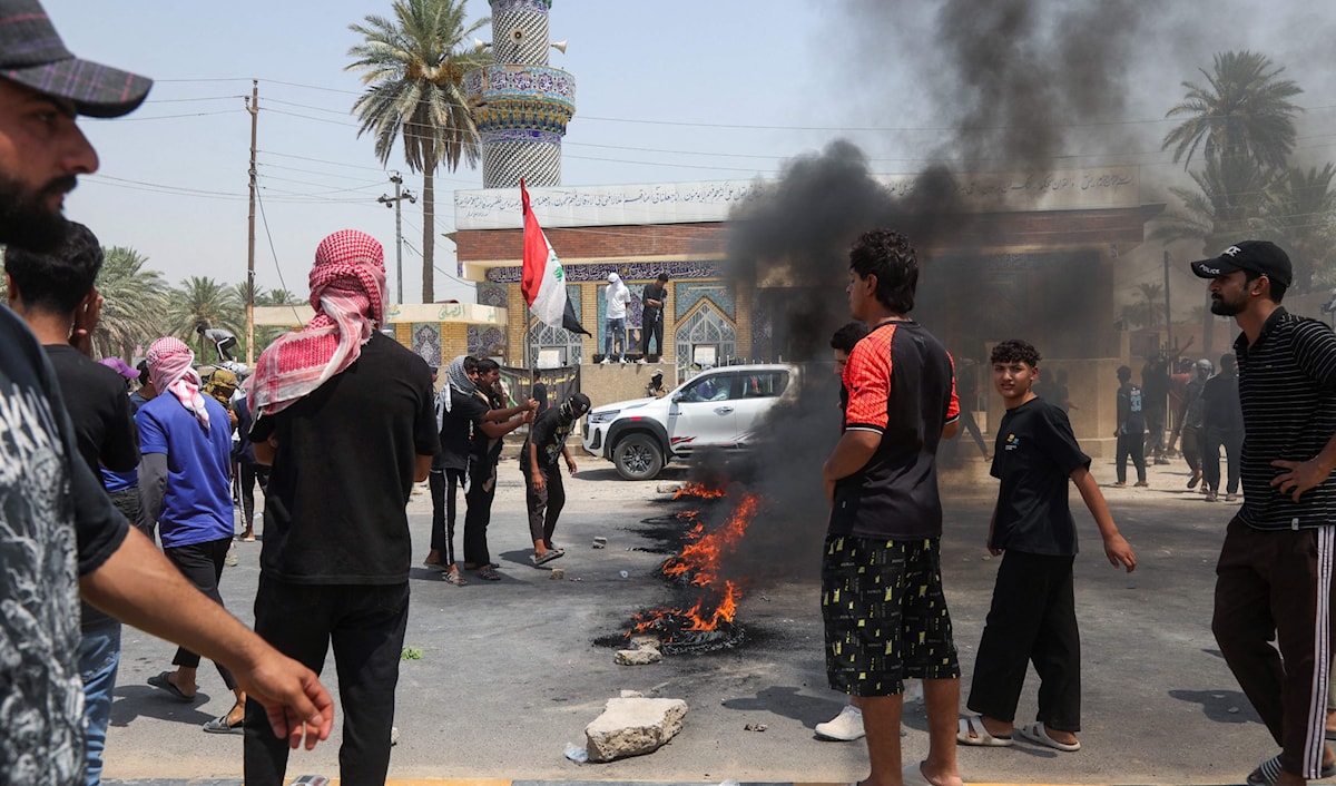 عراقيون يقطعون طريقاً في مدينة الحلة احتجاجاً شح إمدادات المياه (أ ف ب)