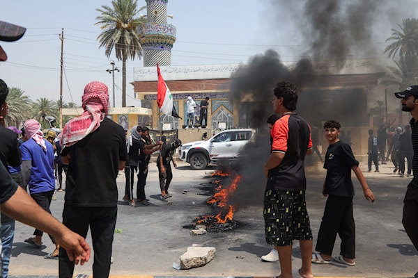 عراقيون يقطعون طريقاً في مدينة الحلة احتجاجاً شح إمدادات المياه (أ ف ب)