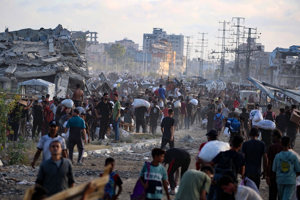 فلسطينيون يحملون المساعدات في شارع صلاح الدين في غزة (أ ف ب)
