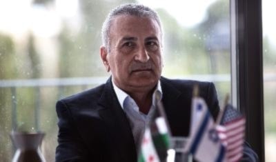 اللبواني يحمل علم «الثورة السورية» وأمامه علما إسرائيل وأميركا خلال مؤتمر صحافي في القدس المحتلة أمس 2014 (ا ف ب)